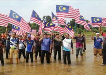 ROSLEE Chik (tengah) mengibarkan Jalur Gemilang dalam programPencegahan Jenayah-Jihad Dadah dan Penghayatan Bulan Kemerdekaan Ke-63 di Kampung Kuala Menjing, Hulu Terengganu, hari ini.