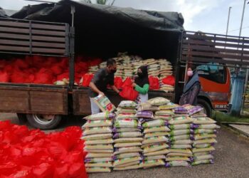Rosol Wahid (kiri) menyampaikan barangan keperluan harian di bawah Program Bakul Makanan kepada penerima di perkarangan Balai Raya Kampung Tajin, Hulu Terengganu, hari ini
