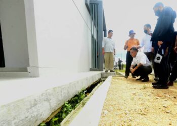 JOHARI Harun (duduk) melihat keretakan ekoran tanah mendap yang berlaku di sebuah taman perumahan di Tanjung Lumpur di Kuantan, Pahang. - FOTO/SHAIKH AHMAD RAZIF