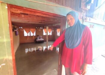 JULIANA Hamzah menunjukkan keadaan air yang masih bertakung di ruang tamu rumahnya selepas hujan lebat baru-baru ini di Kampung Sintok Bugis, Kota Kuala Muda di Sungai Petani. -UTUSAN/NUR SYAZWANA MANSOR