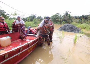 Anggota bomba memindahkan mangsa banjir ke tempat selamat di Kampung Batition, Beluran, Sabah, semalam.