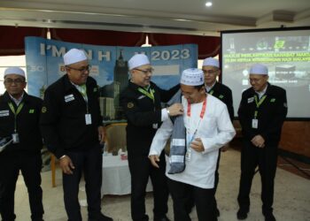 Syed Saleh Syed Abdul Rahman memakaikan jaket sahabat maktab kepada salah seorang jemaah di Mekah, semalam.