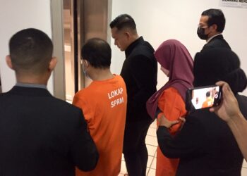 PASANGAN suami isteri yang disyaki melakukan salah guna kuasa dan membuat tuntutan palsu dibawa keluar dari Mahkamah Majistret Kuala Terengganu, Terengganu, hari ini. - UTUSAN/TENGKU DANISH BAHRI TENGKU YUSOFF