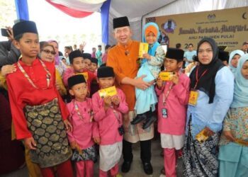 SALAHUDDIN Ayub mendukung seorang kanak-kanak sambil bergambar bersama sempena Rumah Terbuka Aidilfitri Ahli Parlimen Pulai di Taman Rekreasi Taman Uda Utama, Johor Bahru, semalam. - UTUSAN/RAJA JAAFAR ALI