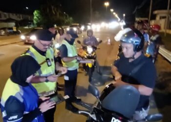 MOHD.Misuari Abdullah (dua dari kiri) memeriksa lesen memandu seorang penunggang motosikal di Jalan Pasir Hor - Kubang Kerian Kota Bharu, Kelantan semalam. -UTUSAN/ROHANA MOHD.NAWI