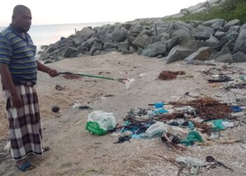 SAMSUDDIN DAUD menunjukkan longgokan sampah sarap yang ditinggalkan pengunjung di Pantai Nusuk, Sabak,  Kota Bharu, semalam.– UTUSAN/ROHANA MOHD. NAWI