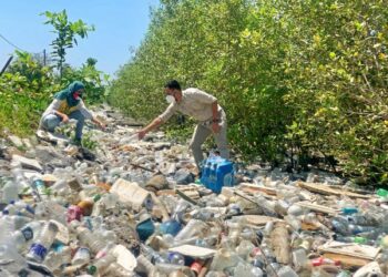 ROSNANI NAZRI dan Syamil Abd. Rahman berdiri di atas timbunan sampah sarap di pesisir Pantai Keria, Sungai Padang, Perlis, semalam. - UTUSAN/MOHD. HAFIZ ABD. MUTALIB