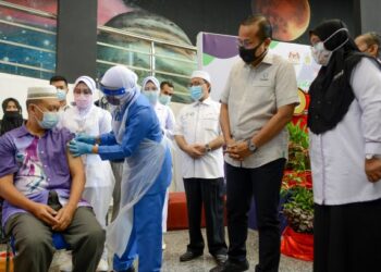 AHMAD SAMSURI MOKHTAR (dua kanan) memerhatikan seorang warga emas menerima suntikan vaksin Covid-19 di Pusat Sains dan Kreativiti Terengganu (PSKT) di Kuala Terengganu hari ini.