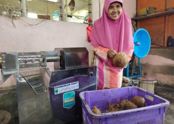 SALMAH Ahmad melihat stok kelapa untuk perniagaan santan diusahakannya di Kampung Chuai, Rembau baru-baru ini.-UTUSAN/NOR AINNA HAMZAH.