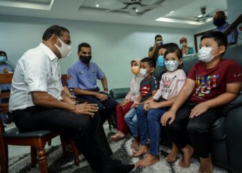 M. Saravanan (kiri) bersama Ketua Eksekutif Perkeso, Datuk Seri Dr Mohammed Azman Aziz Mohammed (dua dari kiri) menyantuni lima beradik yang menjadi yatim piatu selepas kehilangan ibu bapa mereka akibat jangkitan Covid-19 di Kota Perdana, Seri Kembangan, Selangor. - UTUSAN/FARIZ RUSADIO