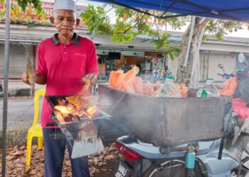 SALLEH Mahmood membakar sate di atas motosikalnya di tepi Jalan Utama Taman Ayer Keroh Height, Ayer Keroh, Melaka. – UTUSAN/MUHAMMAD SHAHIZAM TAZALI