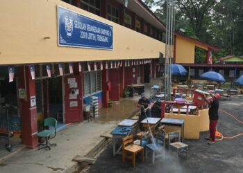 KAKITANGAN Sekolah Kebangsaan  Kampung La, Besut membersih meja dan peralatan kelas yang ditenggelami banjir, hari ini. - UTUSAN/PUQTRA HAIRRY ROSLI