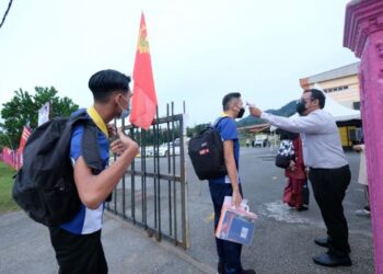 SEORANG guru memeriksa suhu pelajar yang memulakan sesi persekolahan secara bersemuka  di Sekolah Menengah Kebangsaan (SMK) Mahsuri, Langkawi. - UTUSAN/NUR AMALINA AZMAN