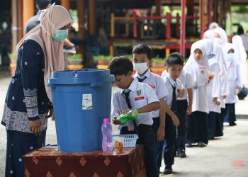 Seorang guru, Nor Emillia Redzuan, membantu murid-murid membasuh tangan di hari pertama pembukaan semula sesi persekolahan di Sekolah Kebangsaan Tunku Abdul Rahman Putra, Kuala Nerang, Kedah. Mingguan/ Shahir Noordin.