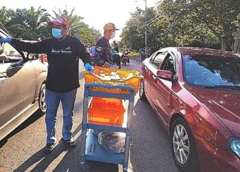 AHLI Jawatankuasa Masjid Kampung Jenjarom, Kuala Langat mengagihkan bantuan makanan kepada orang ramai secara pandu lalu di luar pekarangan masjid. - UTUSAN/
ABDUL RAZAK IDRIS