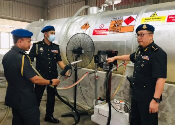 ANGGOTA KPDN memeriksa tangki berisi minyak disyaki diesel yang dirampas dalam serbuah di sebuah premis di Kawasan Perindustrian Silibin, Ipoh semalam. - UTUSAN/KPDN