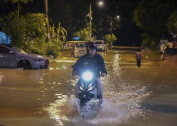 SEORANG penunggang motosikal melalui jalan dinaiki air di Taman Pasir Mas, Sg Chua, Kajang, Selangor hari ini.