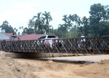 PENDUDUK berkenderaan melintasi Sungai Kupang menggunakan jambatan sementara yang siap dipasang di Kampung Iboi, Kupang, Baling, Kedah. - UTUSAN/IQBAL HAMDAN