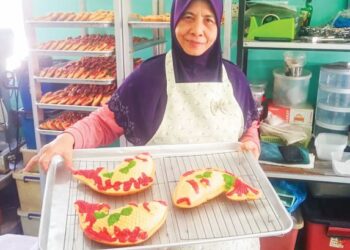 PUJIAH Baharan menunjukkan bahulu ikan koi hasil air tangannya di Klang, Selangor. - UTUSAN/ABDUL RAZAK IDRIS