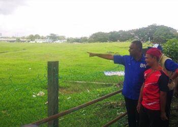 D. KAJENDRAN (kiri) bersama penduduk meninjau lokasi air mula melimpah setiap kali hujan lebat di kawasan Taman Mantap, Shah Alam, Selangor.- UTUSAN/ABDUL RAZAK IDRIS