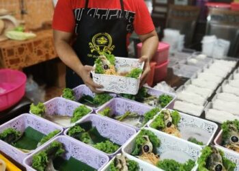 MOHD Taftazany Ab. Aziz bersama Siakap Bakul yang siap dimasak untuk dijadikan hadiah atau tanda ingatan ketika musim pandemik di Kota Jembal, Kota Bharu, Kelantan. - UTUSAN/ROHANA MOHD. NAWI