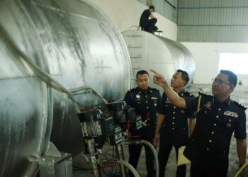 MUHAMAD RADZI Johari (kiri) menunjukkan tangki minyak diesel subsidi yang disimpan di pusat pengumpulan di gudang lama, Indera Mahkota di Kuantan, Pahang. - UTUSAN/DIANA SURYA ABD WAHAB