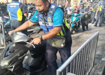 ANGGOTA penguatkuasa MPM menyita motosikal yang di parkir di laluan berbumbung untuk pejalan kaki di Pulau Pangkor. - UTUSAN/IHSAN MPM