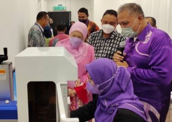 AHMAD Faruz Kurcheri@Huzairi (kanan) menerangkan mengenai perkhidmatan yang ditawarkan di kedai emasnya kepada Azizah (tengah) pada Majlis Perasmian Kedai Emas Nur Jannah Sdn. Bhd. di pekan Kuala Pilah, hari ini.-UTUSAN/NOR AINNA HAMZAH.