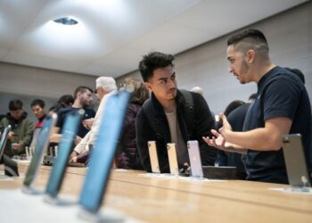 KAKITANGAN Apple (kanan) melayan seorang pengunjung di kedai syarikat itu di New York, semalam. – AFP