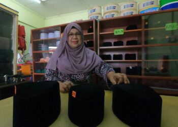 HASNISALFINA Mohd. Yunus menunjukkan sebahagian songkok yang disiapkannya di kedai songkok Seri Warisan, Kuala Pilah, Negeri Sembilan, hari ini.- UTUSAN/ZAKKINA WATI AHMAD TARMIZI