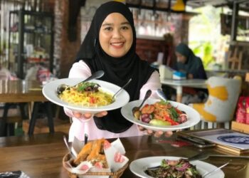 HAZLINA Hassan menunjukkan menu Spageti Masak Lemak Cili Api Daging Salai dan Namtok Kerabu Kambing yang ditawarkan di Miena Kafe di Kampung Gemang, Jeli, Kelantan. - UTUSAN/ROSLIZA MOHAMED