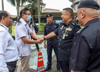 AZMI Sharom (dua kiri) bersalaman dengan Ketua Polis Daerah Putrajaya, ACP A. Asmadi Abdul Aziz (dua kanan) ketika hadir meninjau proses mengundi awal di IPD Putrajaya. - UTUSAN/FAISOL MUSTAFA