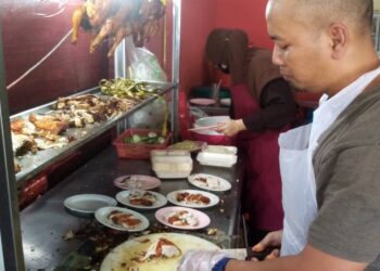 ABDUL Aziz Imran menyediakan nasi ayam untuk pelanggan di gerainya di Seksyen 6, Shah Alam, Selangor. - UTUSAN / MOHAMAD NAUFAL MOHAMAD IDRIS