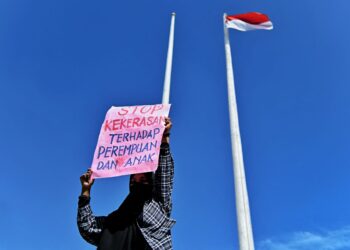 SEORANG wanita memegang poster 'hentikan kekerasan terhadap perempuan dan anak' semasa protes di Banda Aceh.-AFP