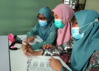 SUHAINI Harun (tengah) membantu anak kembarnya, Nur Sofiya Izzati Mohd. Sapawi (kanan) dan Nur Sofiya Izzah (kiri) menggunakan alat peranti ketika Pengajaran dan Pembelajaran di Rumah (PPdR) di Felda Tekam Utara di Jerantut, Pahang. - UTUSAN/HARIS FADILAH AHMAD
