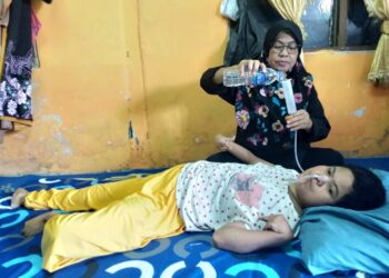 UMI Kalsum Ree menguruskan keperluan Norjan Ahmad yang menghidap Cerebral Plasy (CP) ketika ditemui di rumahnya di perkampungan nelayan Kuala Juru, Butterworth, Pulau Pinang, baru-baru ini.