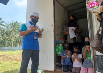 JUNAIDAH Abd. Samad bersama anak-anak mengaminkan doa yang dibaca wakil MAINJ ketika melawat keluarga itu di sebuah kontena di Kampung Baru Seri Aman, Jalan Kempas Lama Tebrau, Johor. - IHSAN MAINJ
