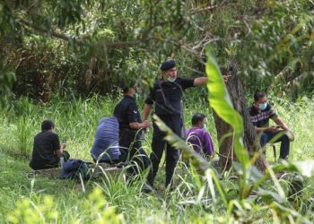 SUSPEK (dua dari kanan) memerhatikan pasukan penyelam berusaha mencari bahan bukti di tasik Taman Putra Perdana, Puchong, semalam. Foto FAISOL MUSTAFA