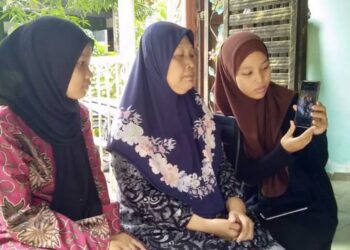NORASHIKIN Ahmad (tengah) ditemani dua lagi anaknya, Siti Dabaitul Adawiyah (kiri) dan Nur Syafawati Aina melihat gambar anak dan cucunya yang maut dalam kemalangan semasa ditemui di rumah mereka di, Gurun, Sungai Petani, hari ini. -UTUSAN/OTHMAN YAHAYA
