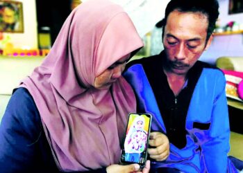 SUZANA Ibrahim dan Mohammad Fadzil Yuso menunjukkan gambar
Nur Aira Awatif yang maut dilanggar kenderaan pacuan empat roda
ketika menunggang basikal di Jalan Delima, Kampung Cacar Baru, Paka,
Dungun, Terengganu, semalam.