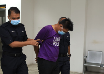 SUSPEK (tengah) diiringi polis untuk perintah reman di Mahkamah Majistret, Kota Bharu, Kelantan hari ini. - UTUSAN/KAMARUL BISMI KAMARUZAMAN