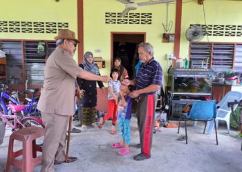 TAJUDDIN Abdul Rahman (kiri) menyampaikan sumbangan peribadi kepada seorang mangsa ribut di Kampung Air Kuning, Pasir Salak hari ini. - UTUSAN