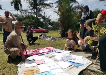 TAJUDDIN Abdul Rahman (kiri) berbual dengan sebuah keluarga yang menjemur buku sekolah anak mereka yang basah terkena air hujan akibat kejadian ribut di Kampung Air Kuning di Pasir Salak. – UTUSAN/AIN SAFRE BIDIN
