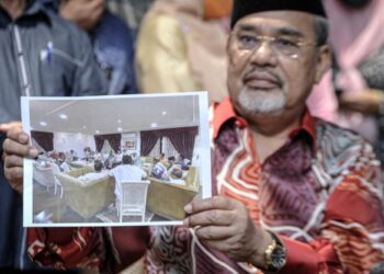 TAJUDDIN Abdul Rahman menunjukkan gambar pemimpin-pemimpin UMNO yang hadir dalam perjumpaan di rumahnya, dalam sidang akhbar, baru-baru ini.- UTUSAN/FAIZ ALIF AHMAD
