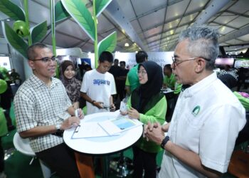 MUHAMMAD Fikri Mohamad Rawi (kanan) beramah mesra dengan sebahagian pengunjung yang mendaftar di kiosk Takaful Ikhlas ketika mengunjungi MSAM 2022 di Port Dickson, hari ini.-UTUSAN/MOHD. SHAHJEHAN MAAMIN.