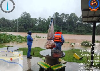 DUA anggota Angkatan Pertahanan Awam Malaysia (APM) Jeli melakukan pemantauan air sungai yang mula melimpahi tebing di Lorong Shahir, Kampung Jeli, Jeli, Kelantan, hari ini. - IHSAN APM KELANTAN