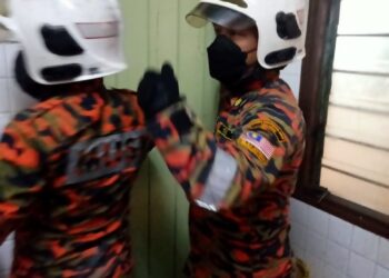 ANGGOTA bomba mengumpil pintu tandas bagi mengeluarkan lelaki warga emas yang terkunci dan meninggal dunia di Taman Guru, Sitiawan, Perak hari ini. - UTUSAN/IHSAN JBPM