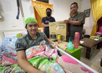 MUHAMMAD Afiq Aiman Shukri (belakang, kiri) menyampaikan sumbangan lampin pakai buang untuk kegunaan Muhammad Faiz Hafizuddin di Kampung Bukit Bidang, Selising, Pasir Puteh, semalam. - UTUSAN/TOREK SULONG