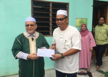 MOHD Amar Nik Abdullah (kiri) menyampaikan cek sumbangan kepada wakil Masjid Al-Alaq di Kampung Pak Kemek, Panji, Kelantan. - UTUSAN/ ROSMIZAN RESDI