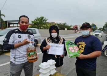 MOHAMAD Naja Nafhan Azman (kiri) dan Mohd. Hafiz Ierfan Rosli (kanan) memberikan bantuan keperluan harian kepada seorang penerima di hadapan SMK Sri Tanjung, di Benut, Pontian, Johor. -UTUSAN/MUHAMMAD ZIKRI